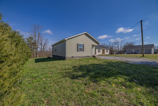 view of property exterior featuring a yard, crawl space, and gravel driveway