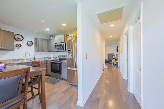 kitchen with recessed lighting, a sink, baseboards, appliances with stainless steel finishes, and light wood finished floors