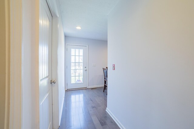 doorway to outside with a textured ceiling, wood finished floors, and baseboards