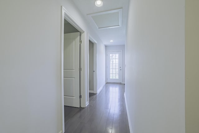 corridor with dark wood-style flooring, attic access, and baseboards