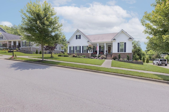 view of front facade with a porch, a front yard, and brick siding