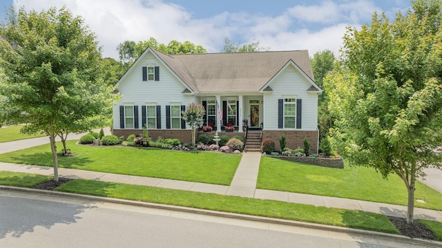 view of front facade with a porch, a front lawn, and brick siding