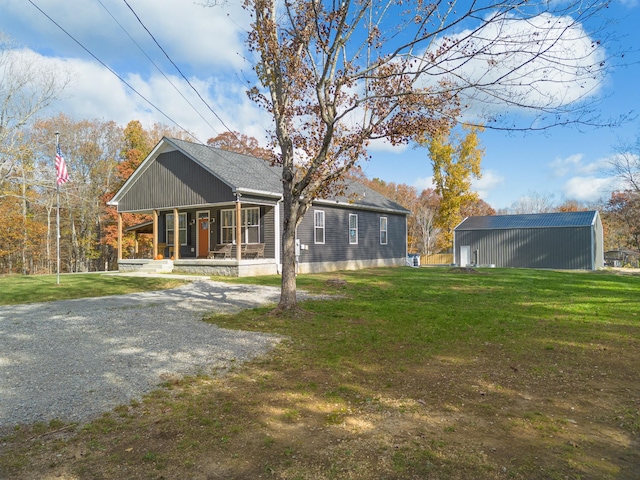 back of house featuring covered porch, a yard, and gravel driveway