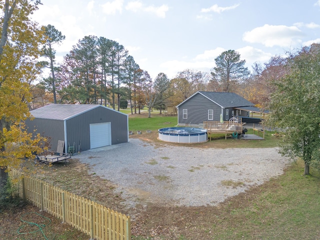 view of yard with driveway, a fenced in pool, a detached garage, an outbuilding, and fence