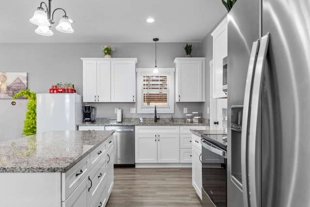 kitchen with appliances with stainless steel finishes, decorative light fixtures, and white cabinets