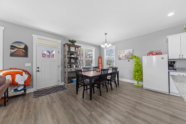 dining space with a chandelier, recessed lighting, wood finished floors, and baseboards