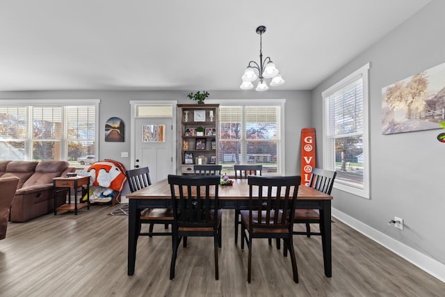 dining space with a chandelier, wood finished floors, and baseboards