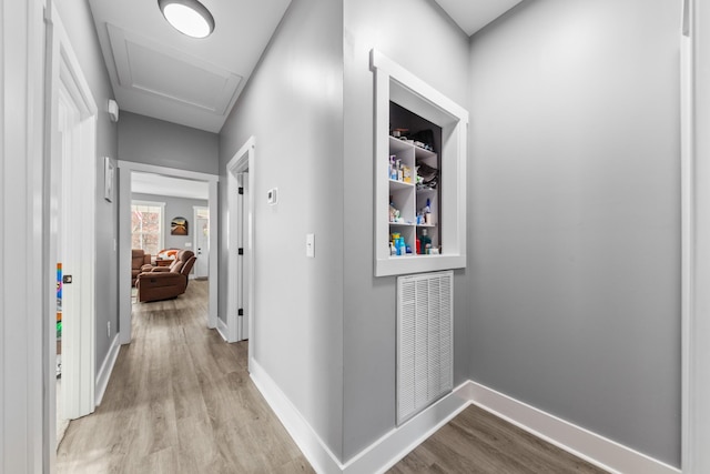 corridor featuring light wood-style floors, visible vents, and baseboards