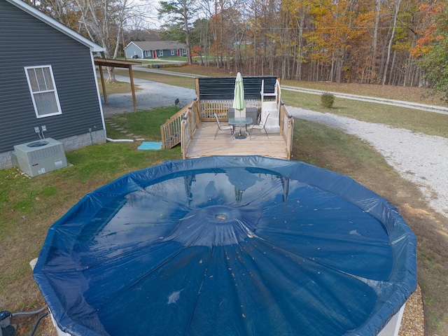 view of swimming pool featuring central AC, a yard, and a wooden deck