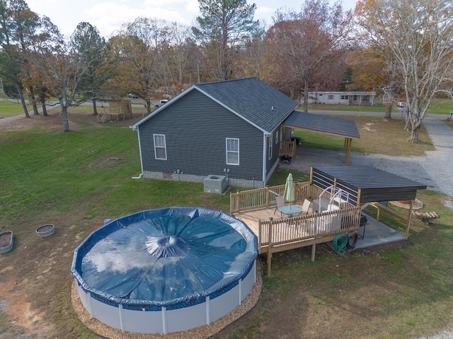 view of swimming pool featuring a deck, a yard, and a covered pool