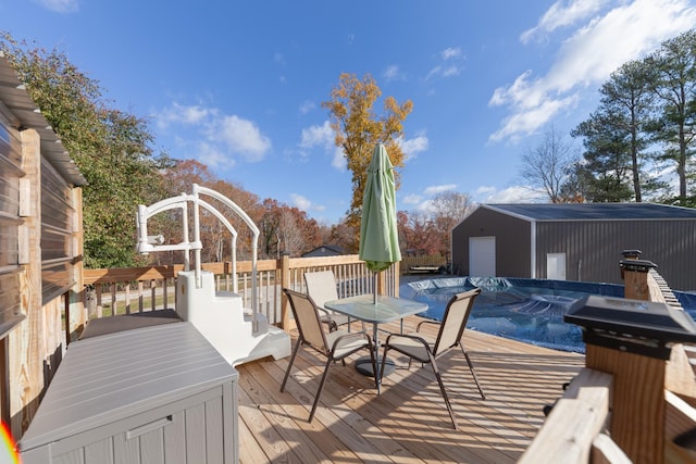 wooden deck with a garage, a covered pool, an outdoor structure, and outdoor dining space