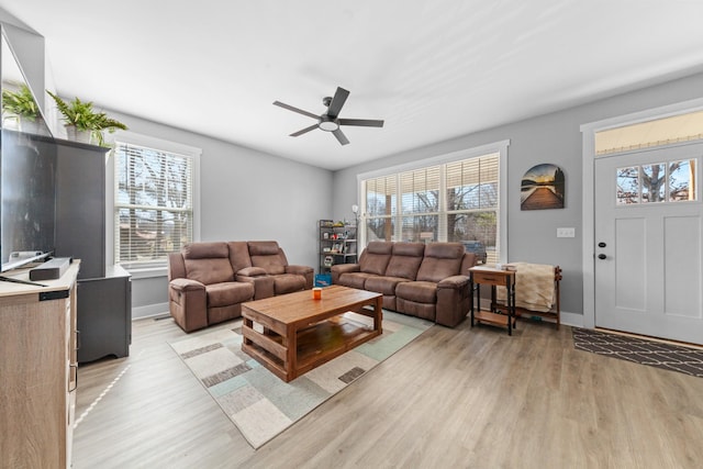 living area with baseboards, light wood-style floors, and a healthy amount of sunlight