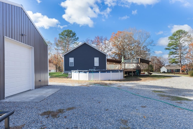 exterior space with a garage, a covered pool, board and batten siding, and gravel driveway