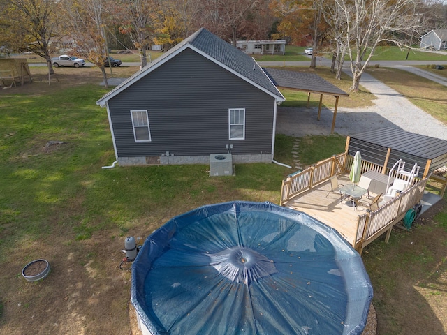 view of pool with a lawn, a wooden deck, and central AC unit