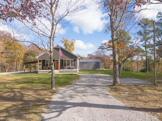 view of front facade with gravel driveway, covered porch, and a front lawn