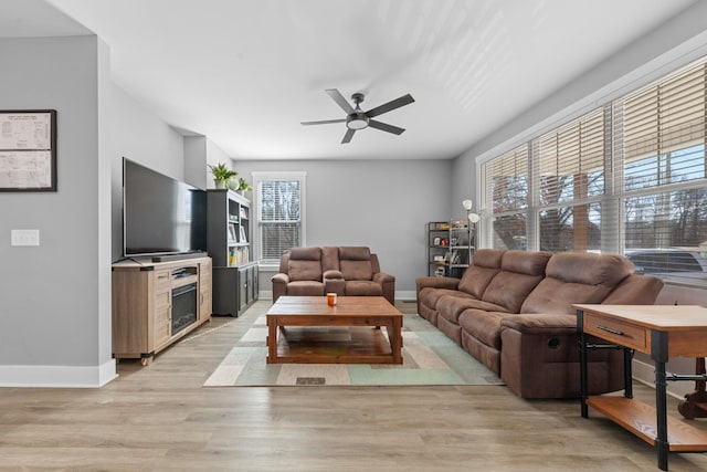 living room with light wood-style floors, baseboards, and a ceiling fan