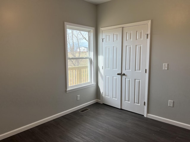 interior space with a closet, dark wood-style flooring, visible vents, and baseboards