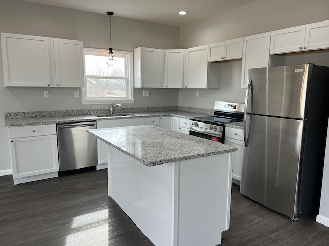 kitchen featuring white cabinets, dark wood-style floors, a kitchen island, appliances with stainless steel finishes, and a sink