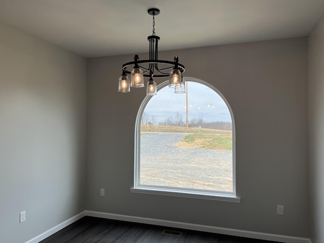 empty room featuring baseboards, visible vents, a chandelier, and dark wood-style flooring