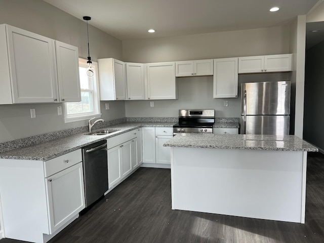 kitchen featuring dark wood finished floors, light stone countertops, stainless steel appliances, white cabinetry, and a sink