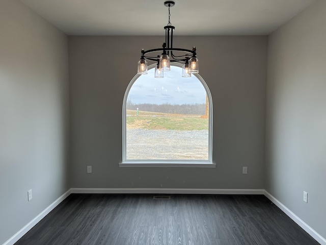 unfurnished dining area featuring an inviting chandelier, visible vents, baseboards, and dark wood finished floors