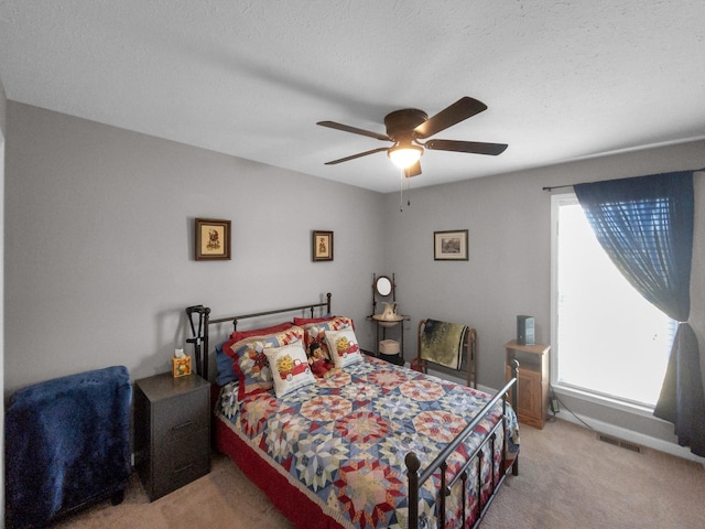 bedroom with a ceiling fan, visible vents, a textured ceiling, and light colored carpet