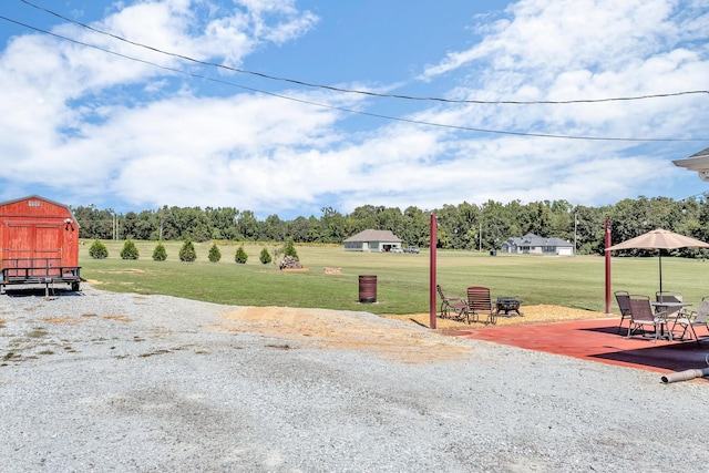 view of yard featuring a storage shed, a patio area, and an outbuilding