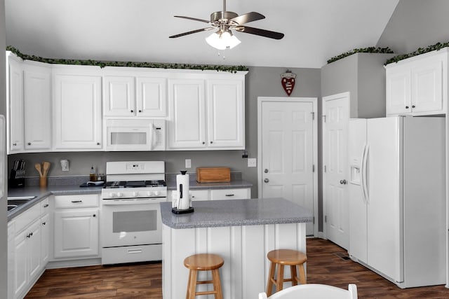 kitchen with white appliances, a breakfast bar area, white cabinets, and a center island