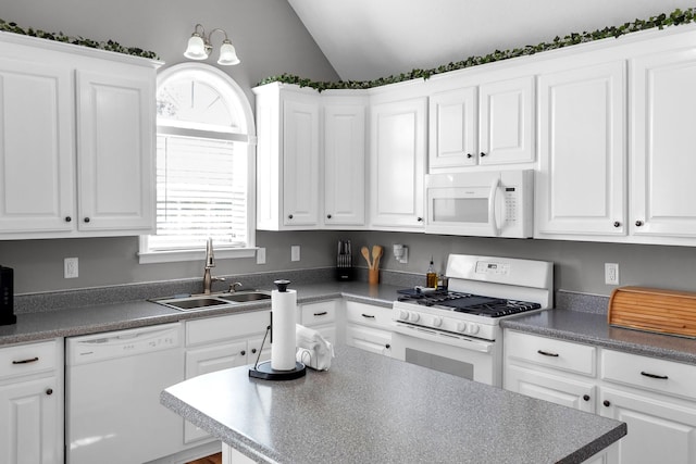 kitchen with white appliances, white cabinets, dark countertops, vaulted ceiling, and a sink