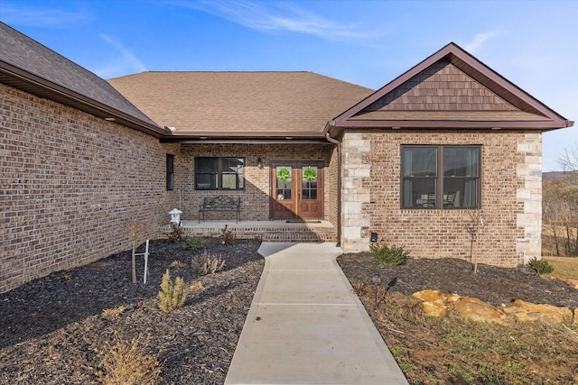 property entrance with a porch, brick siding, and roof with shingles