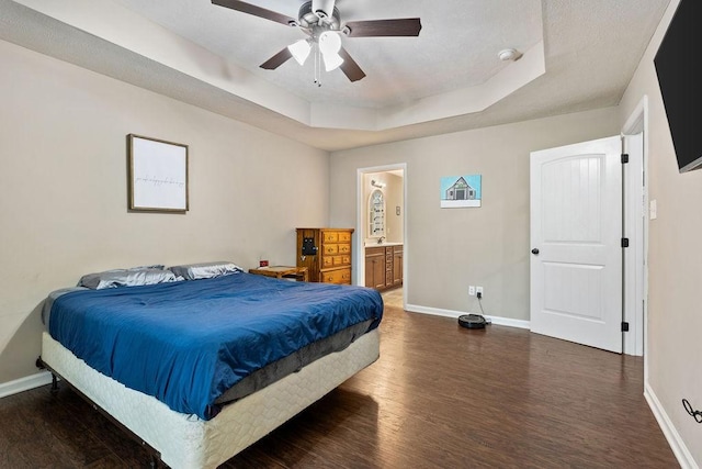 bedroom featuring dark wood-style floors, a tray ceiling, and baseboards