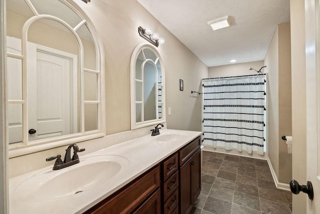 full bath with double vanity, a textured ceiling, shower / bath combo with shower curtain, and a sink