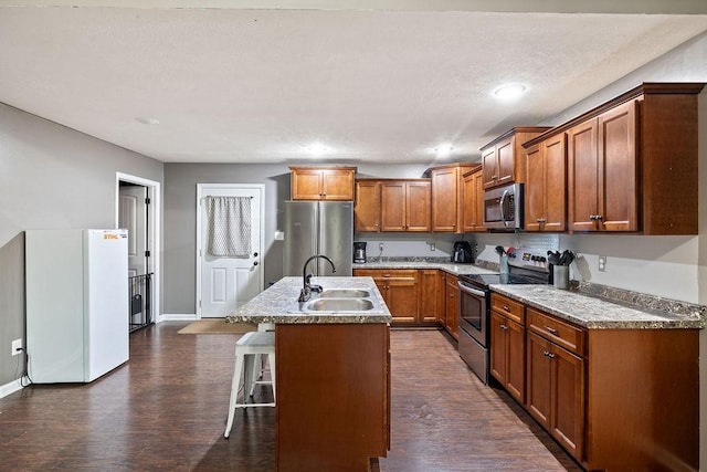 kitchen featuring a sink, stainless steel appliances, an island with sink, and light countertops