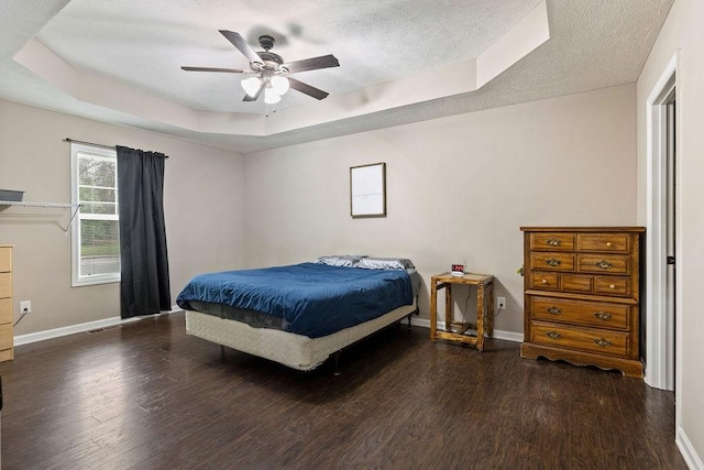 bedroom featuring dark wood-style floors, a textured ceiling, and a raised ceiling