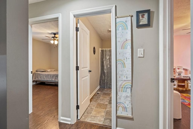 corridor featuring a textured ceiling, light wood finished floors, and baseboards