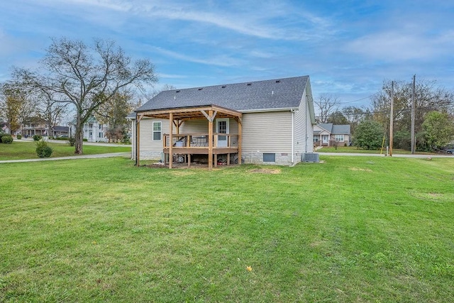 rear view of property with a deck, central AC, a shingled roof, and a lawn