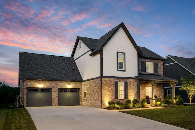 view of front of property with driveway, a shingled roof, an attached garage, a yard, and brick siding