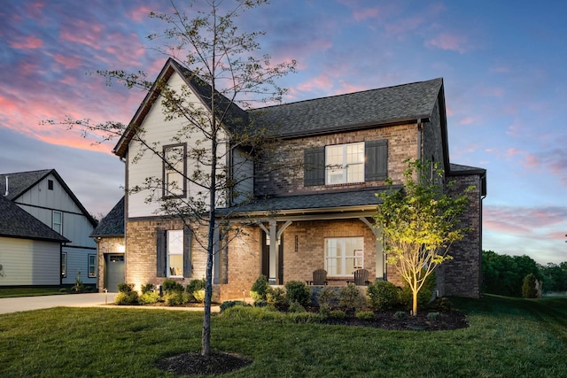 view of front facade with a garage, a shingled roof, concrete driveway, a lawn, and brick siding