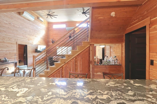 interior space with lofted ceiling, wood walls, and stairs