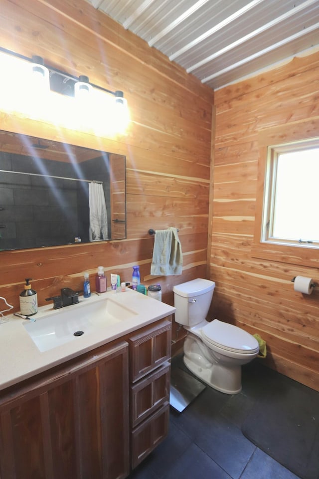 bathroom featuring toilet, tile patterned floors, wooden walls, and vanity