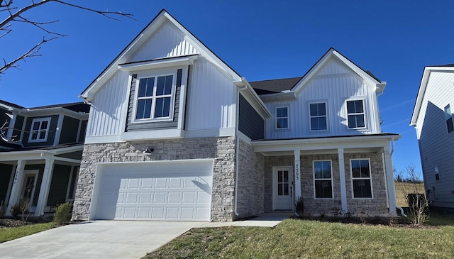 view of front of home with board and batten siding, a garage, stone siding, driveway, and a front lawn