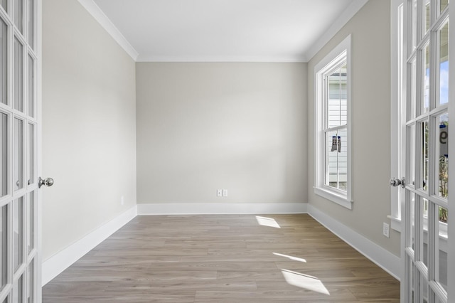 empty room with ornamental molding, french doors, and light wood-type flooring