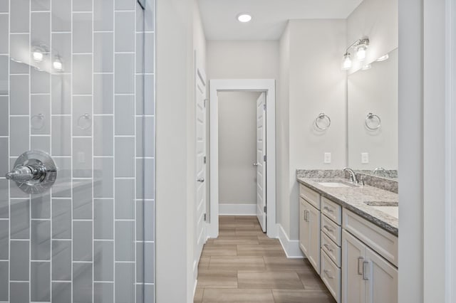 bathroom featuring double vanity, baseboards, a sink, and wood finish floors