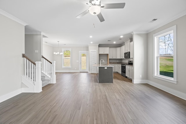 kitchen with white cabinetry, open floor plan, appliances with stainless steel finishes, an island with sink, and pendant lighting