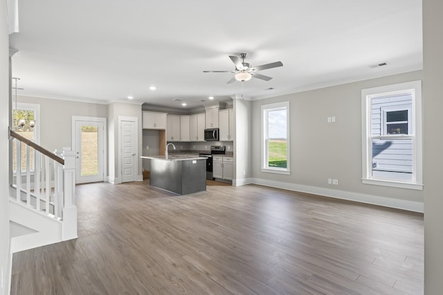 kitchen with a center island with sink, visible vents, open floor plan, stainless steel appliances, and crown molding