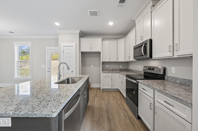 kitchen with stainless steel appliances, an island with sink, a sink, and white cabinetry