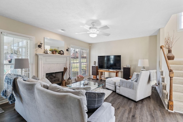 living area featuring ceiling fan, stairs, dark wood finished floors, and a high end fireplace