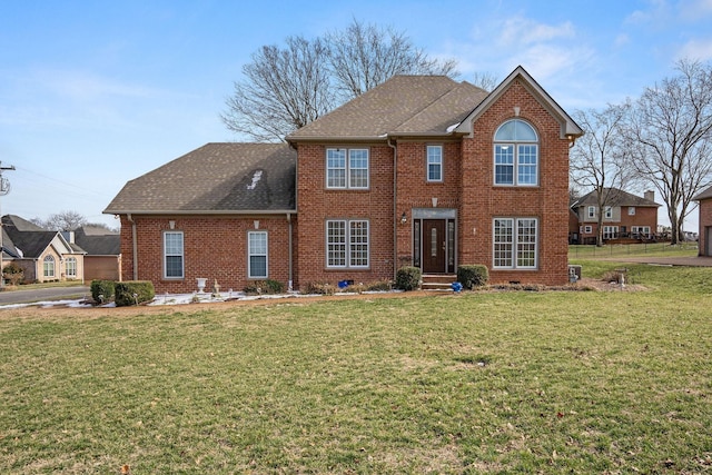 view of front of house with brick siding, a front lawn, and a shingled roof