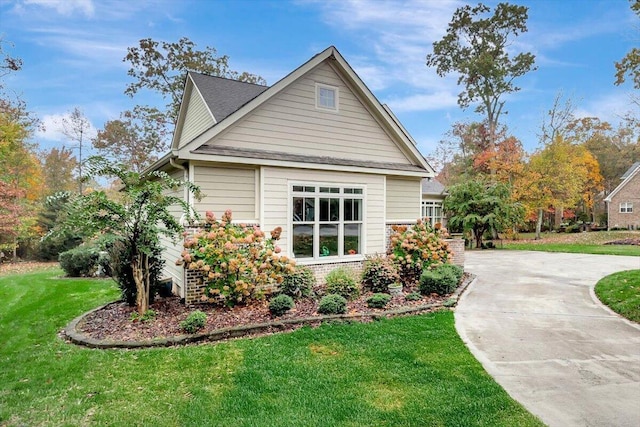 view of home's exterior with a lawn and concrete driveway