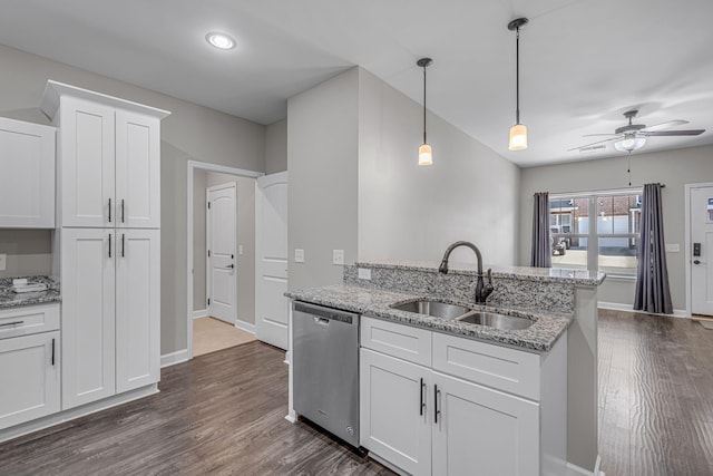 kitchen with light stone counters, dark wood-style flooring, a sink, white cabinets, and stainless steel dishwasher